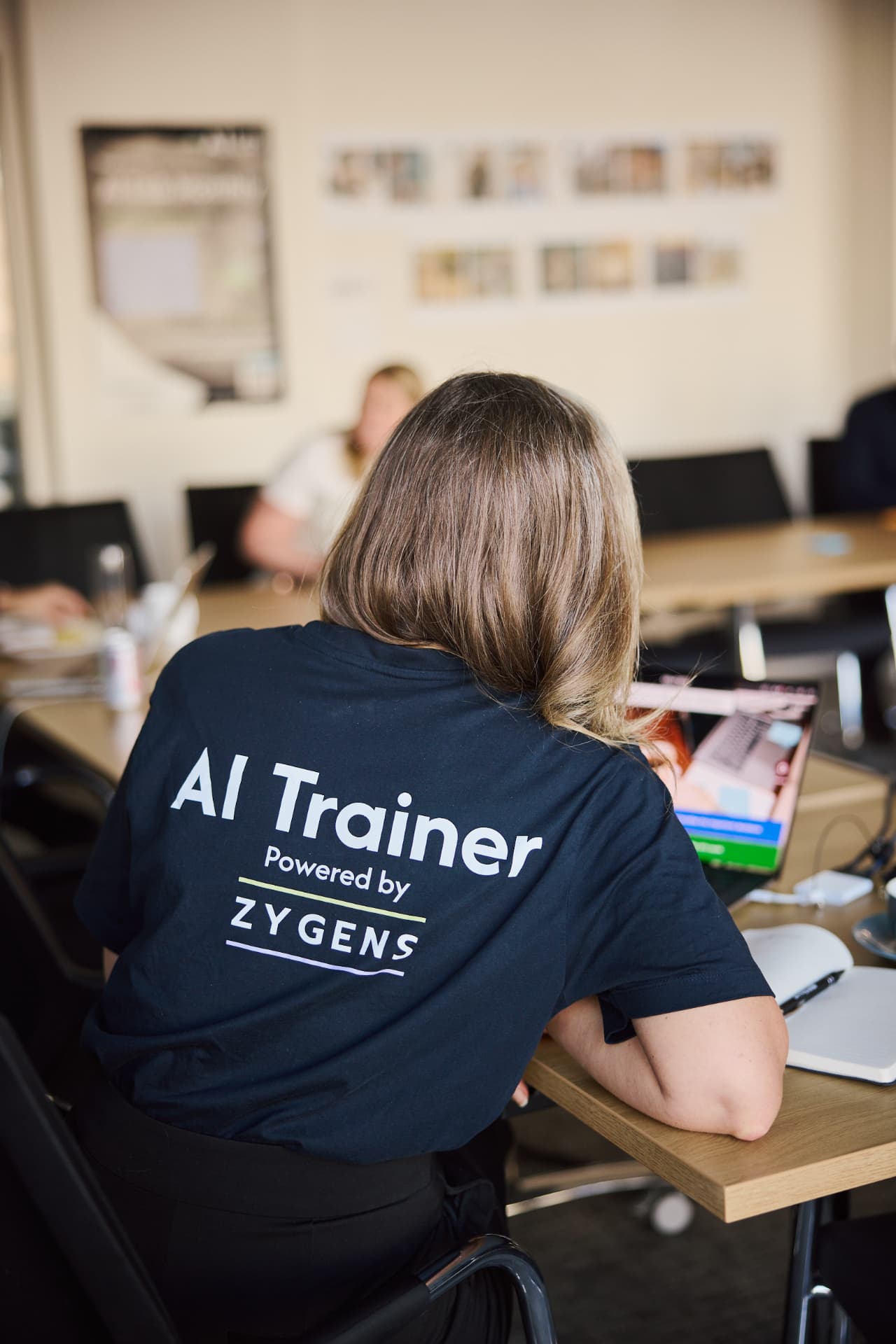 An AI Lab trainer in a branded t-shirt helping a participant during a workshop