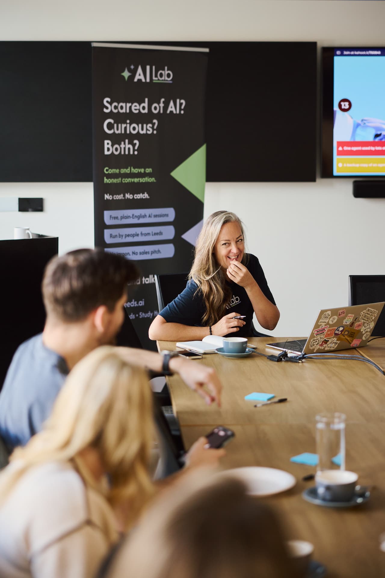 AI Lab facilitator speaking with attendees around a table at a workshop in Leeds